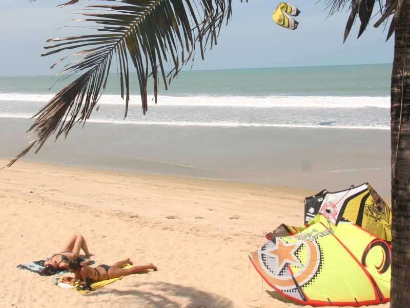 Pessoa sentada na areia de Icaraizinho limpando peixes frescos ao lado de cesta de vime