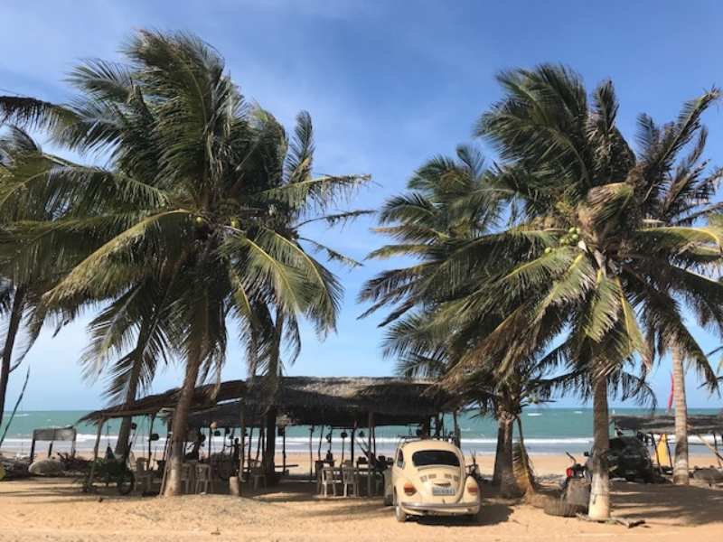 Praticante de kitesurf em voo sobre as ondas da Praia de Caetanos, vento forte e céu azul